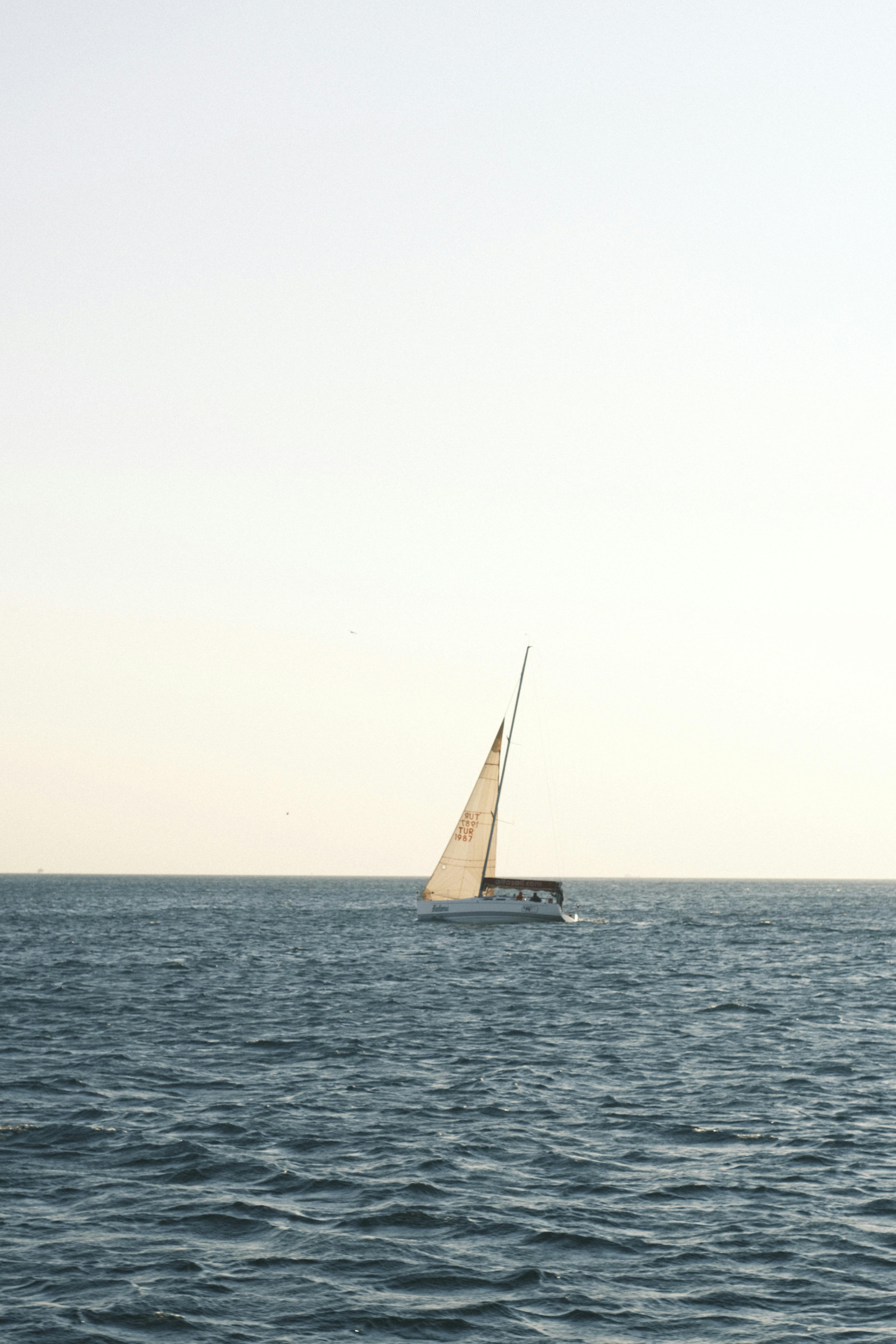 A solitary sailboat glides gracefully across a calm ocean under a clear sky, embodying peace and freedom.