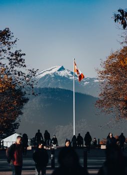 A majestic autumn scene in Vancouver featuring the Canadian flag and snowcapped mountains.