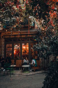 Charming café exterior with people relaxing under warm lights on a cool evening.