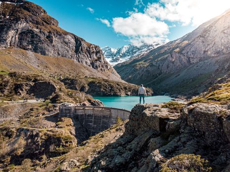 A man stands overlooking a picturesque lake surrounded by mountains in Gavarnie-Gèdre.