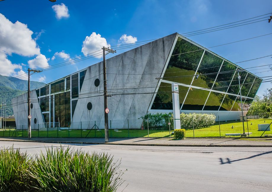 Innovative building design featuring glass panels and concrete structure on a sunny day.