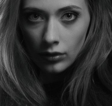 Grayscale close-up portrait of a woman with expressive eyes and flowing hair.