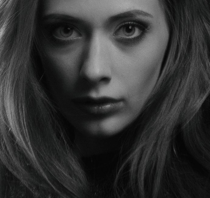 Grayscale close-up portrait of a woman with expressive eyes and flowing hair.