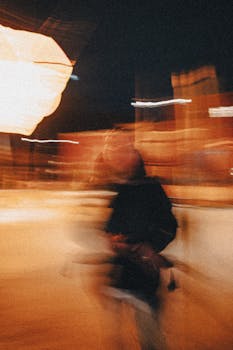 Dynamic motion blur of a person in a nighttime urban setting with warm lighting.