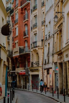 A picturesque street in Paris's Marais district featuring classic architecture and pedestrians on the sidewalk.