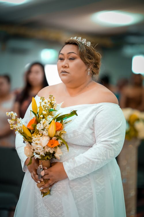 Woman in White Long Sleeve Dress Holding Bouquet of Flowers