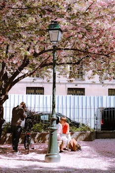 Couple enjoys a spring day under cherry blossoms in a Parisian park.
