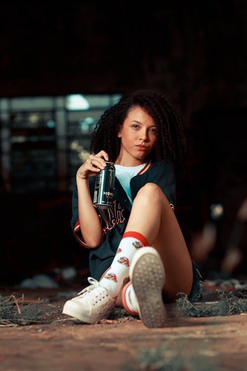 Woman with Energy Drink Sitting on Ground