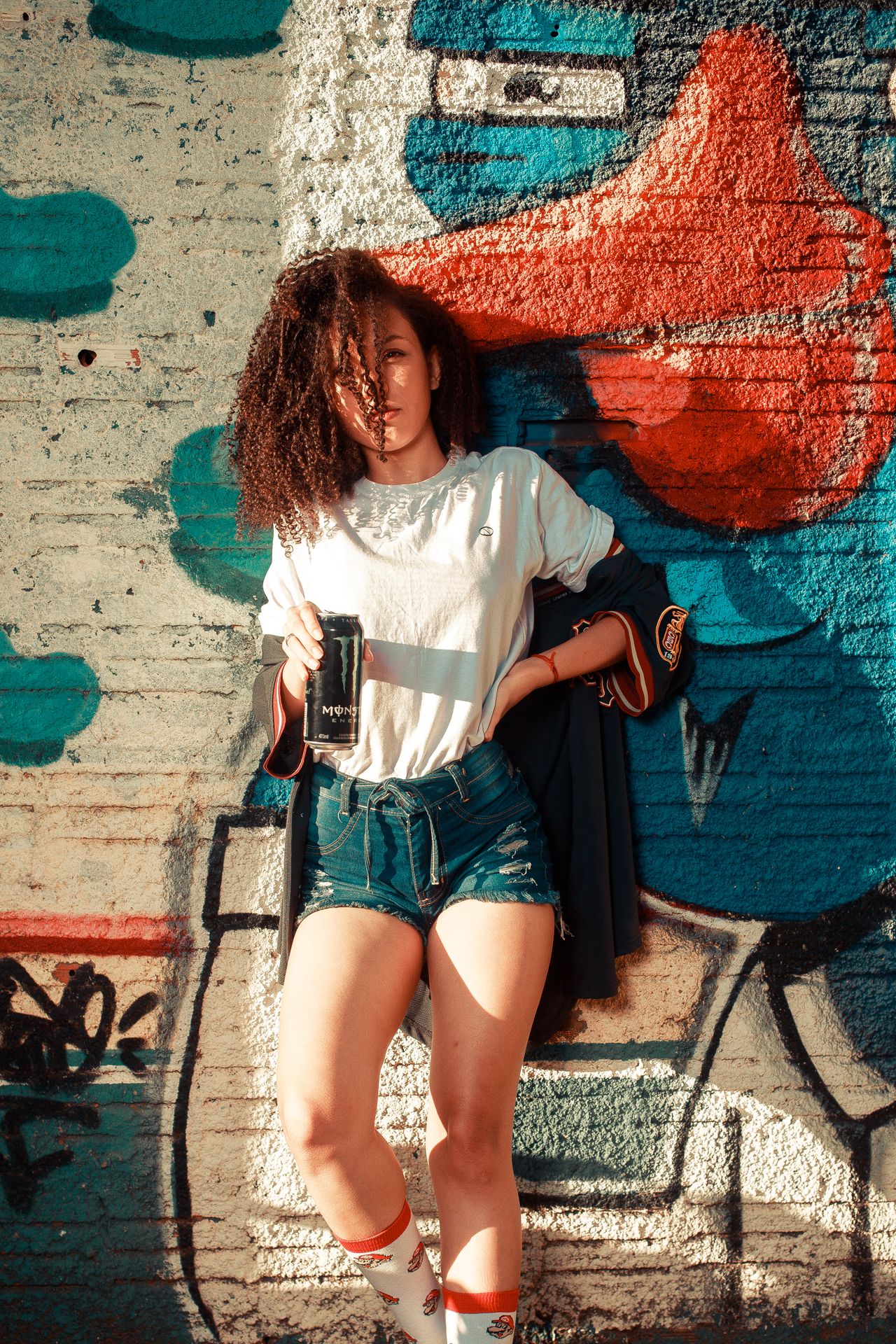 Woman in a white tee and denim shorts with a jacket draped over her shoulders