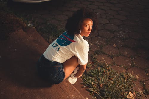 Woman in White T-shirt and Denim Shorts Sitting on the Stairs