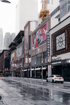 Contemporary street view of downtown Toronto on a rainy day, showcasing modern architecture and vibrant urban life.