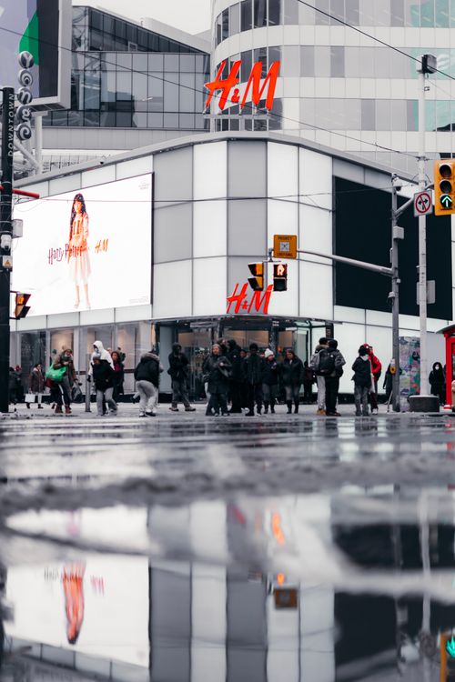 Free City street scene with pedestrians and building reflected in puddle. Stock Photo