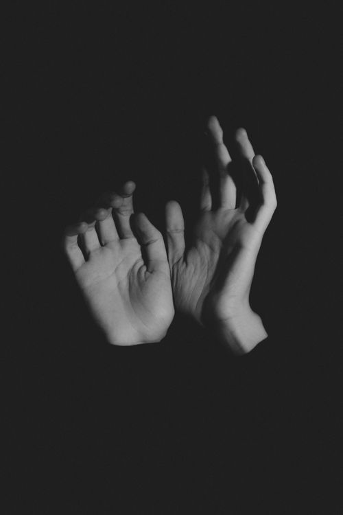 Free A dramatic black and white photo of hands raised against a dark background, conveying emotion and mystery. Stock Photo