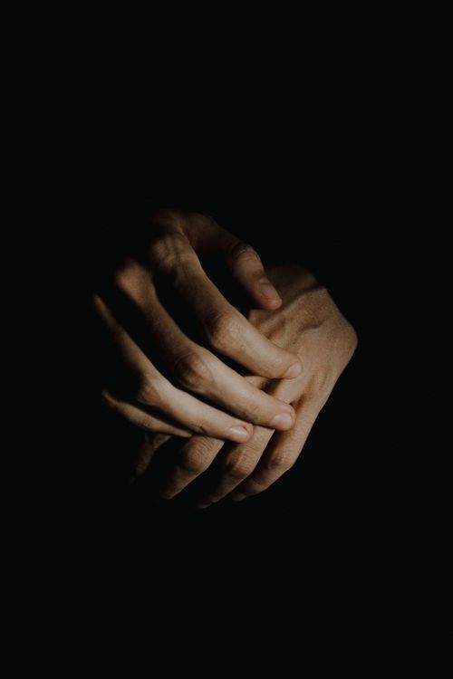 Free A dramatic close-up of hands clasped together against a dark background, emphasizing texture and emotion. Stock Photo