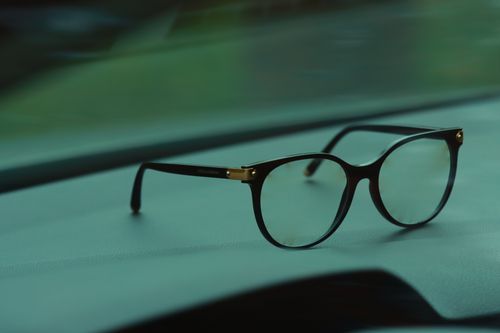 Free Close-up of stylish black eyeglasses resting on a car dashboard. Perfect for eyewear and fashion themes. Stock Photo