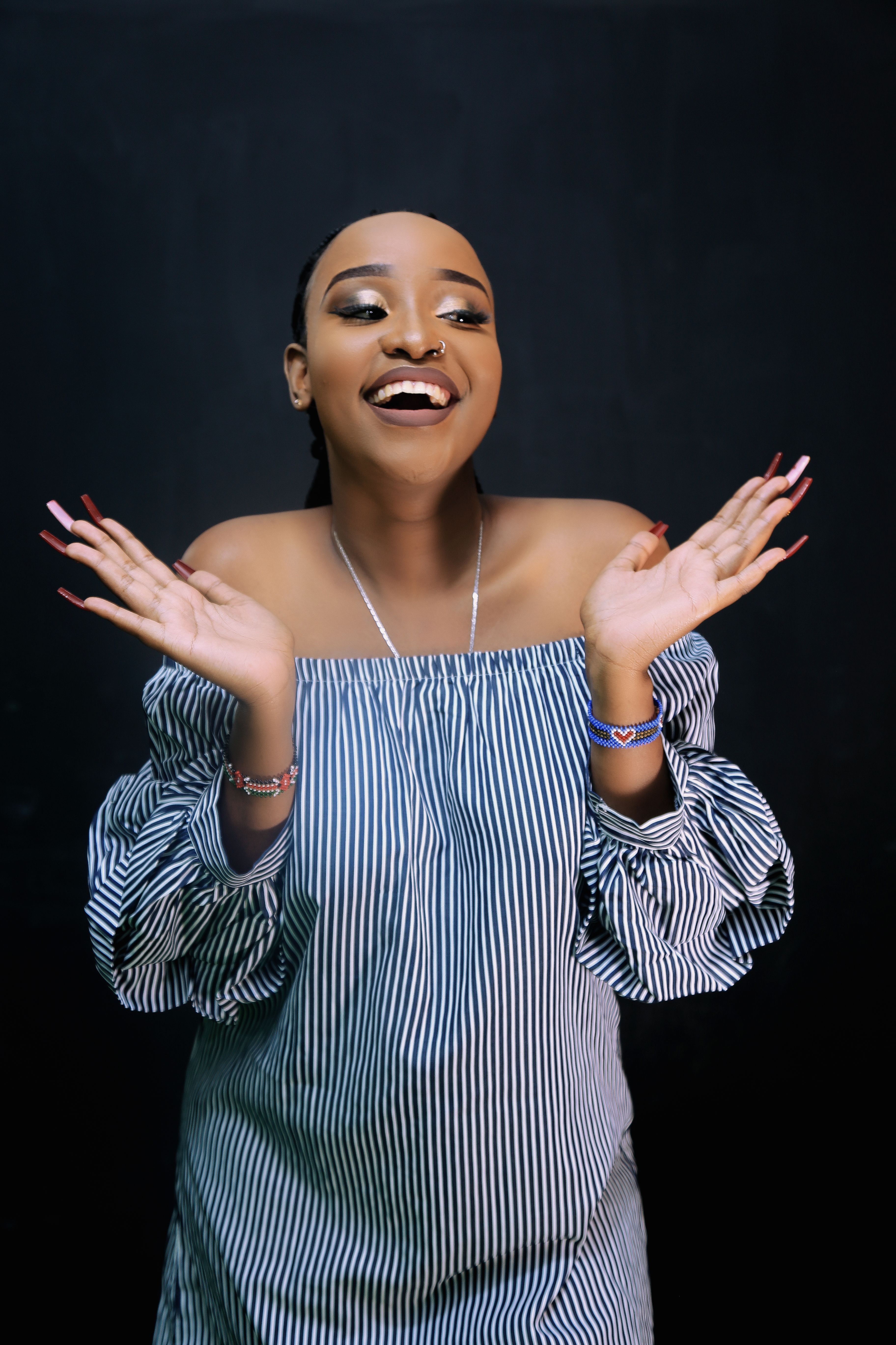 Happy African American woman in an off-shoulder dress posing in a studio.