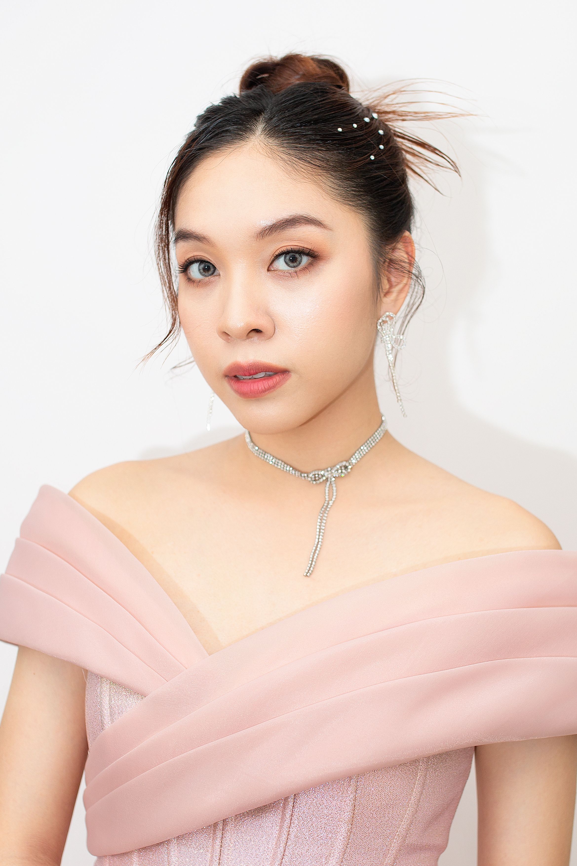 Portrait of a stylish woman in an off-shoulder dress with elegant jewelry.