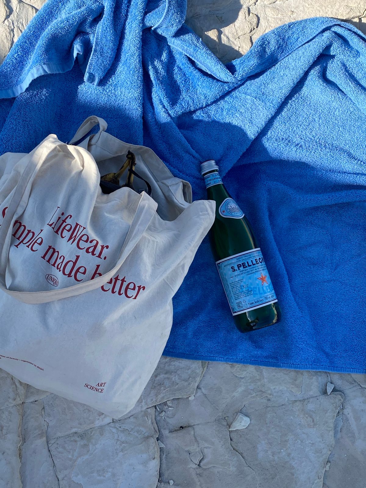 Beach bag, water bottle and towel arranged on the sand