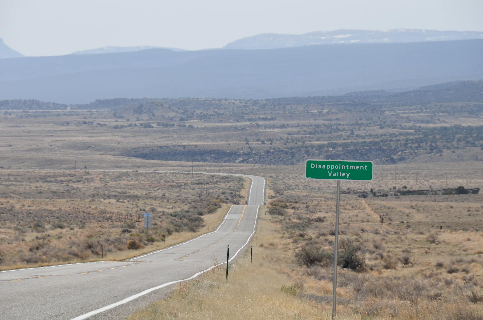 A winding road with a sign for Disappointment Valley in Hanksville, Utah.