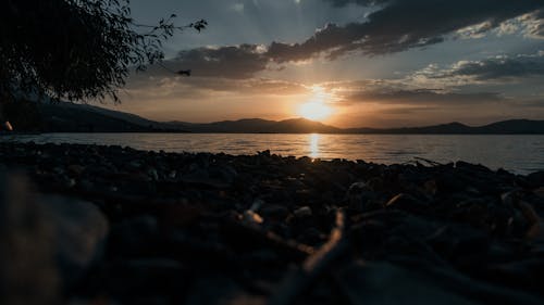 View of a Beach, Body of Water and Mountains in Distance at Sunset