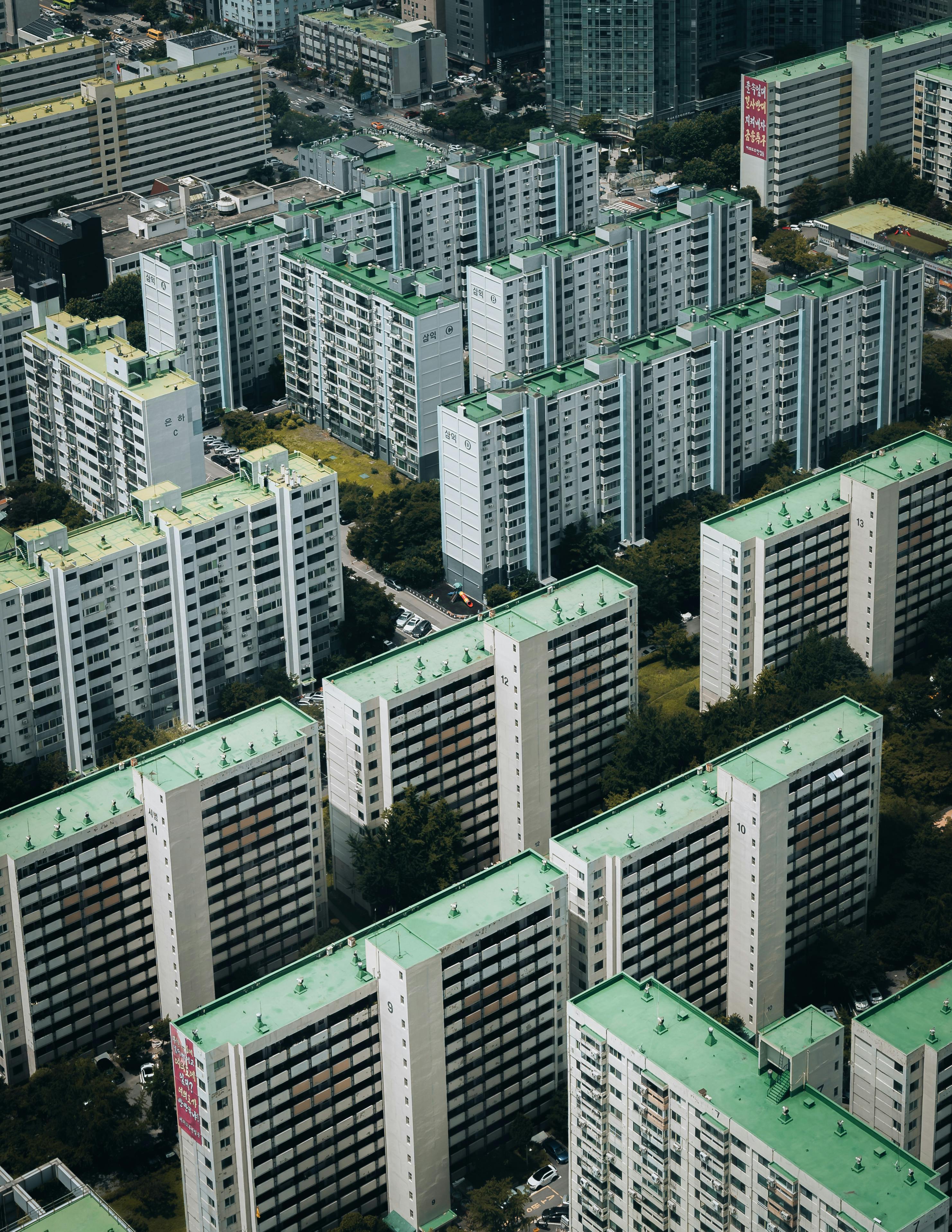Urban cityscape featuring densely packed apartment buildings with green rooftops in Seoul, South Korea.