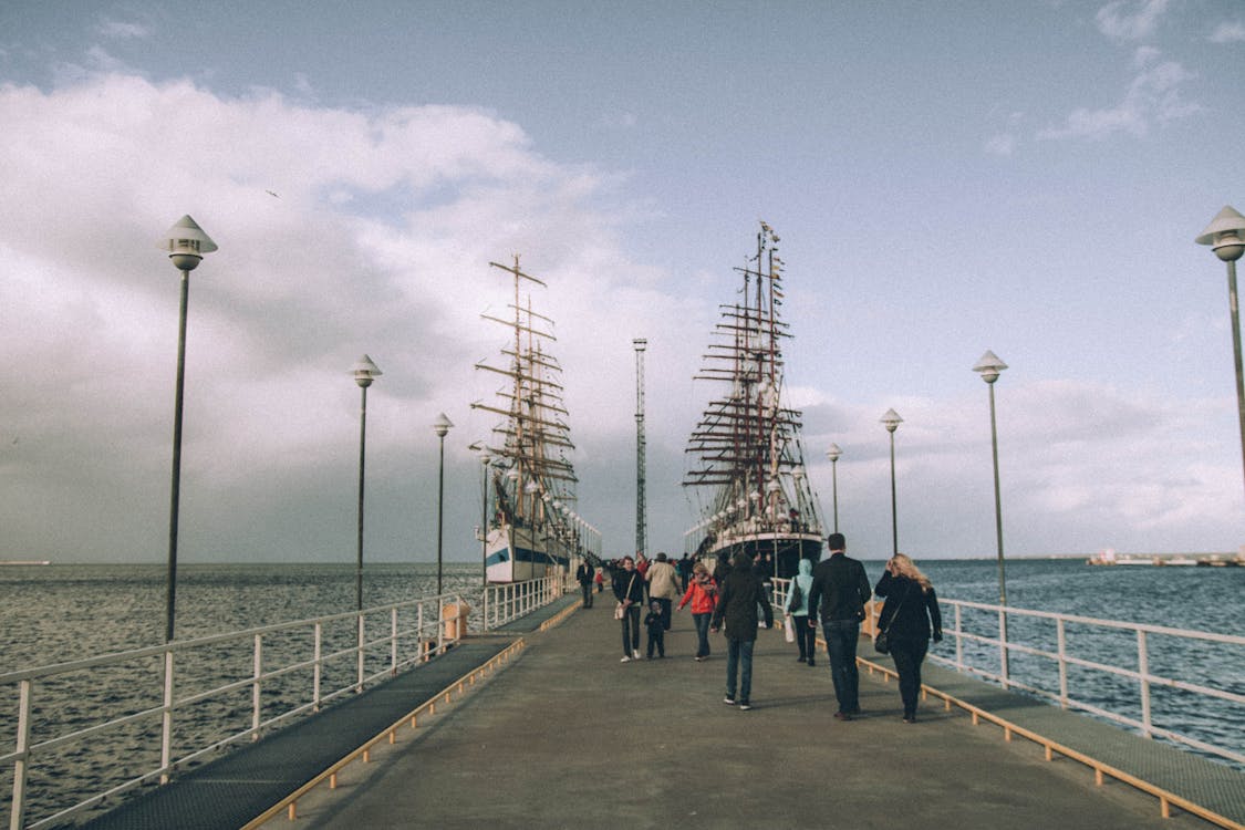 People Walking on Bridge Under Gray