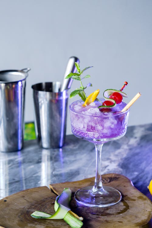 Close-up of a Purple Cocktail with Fruits Standing on a Wooden Cutting Board