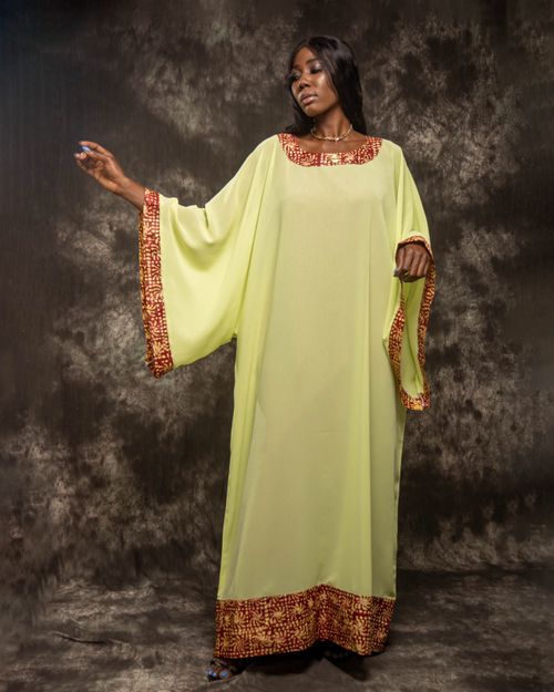 Free Portrait of a stylish woman wearing a traditional yellow dress, raising hand. Stock Photo
