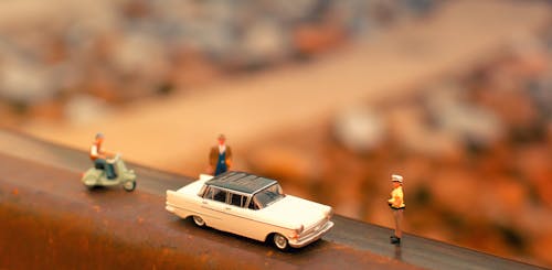 Free Tilt-shift Photography of Classic Car Scale Model Near Two Figurines Stock Photo