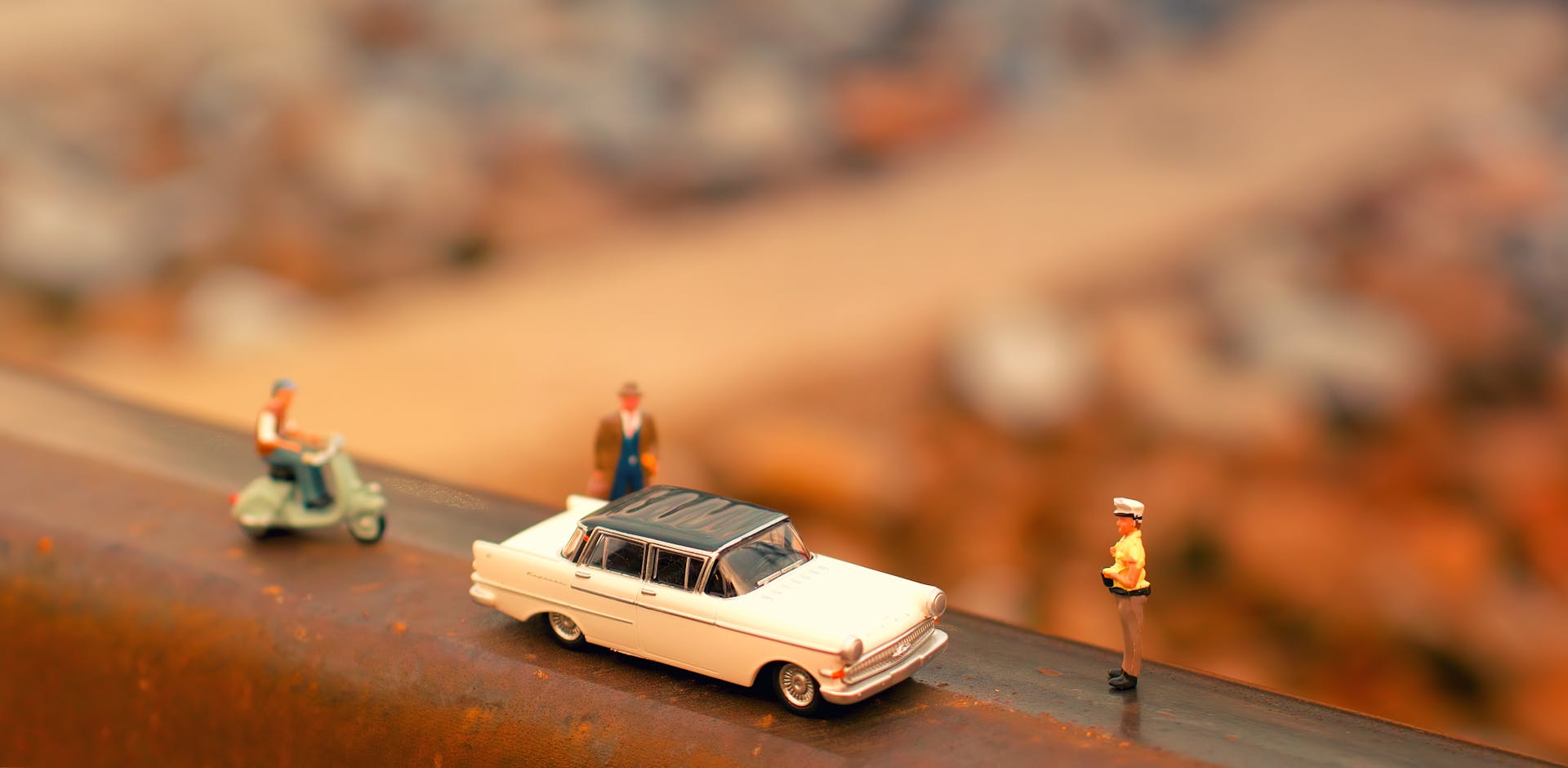 Tilt-shift Photography of Classic Car Scale Model Near Two Figurines