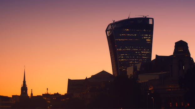 日落天空映衬着伦敦天际线的剪影，标志性的对讲机建筑格外醒目