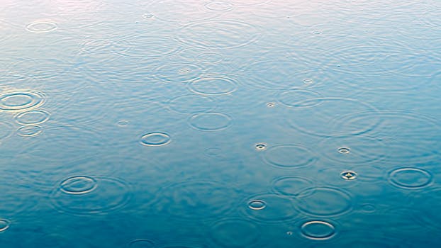 雨滴的特写镜头在平静的水面上激起涟漪