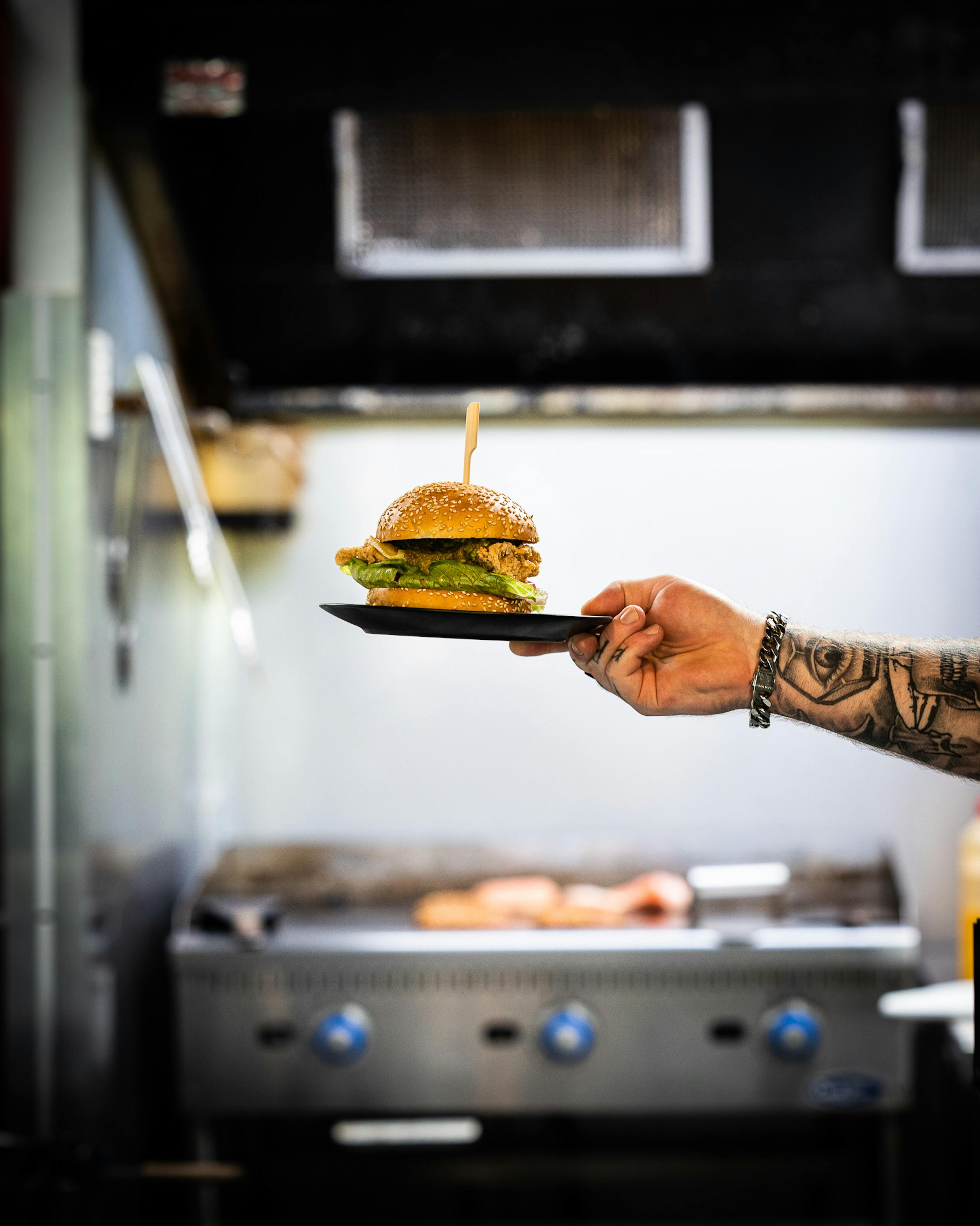 A Tattooed Person Holding a Plate of a Delicious Chicken Sandwich