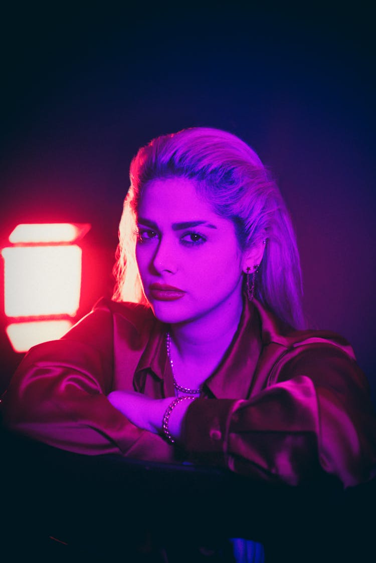 Portrait Of Beautiful Woman In Satin Shirt Illuminated By Purple Light