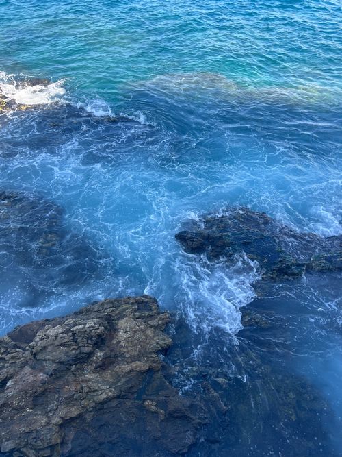 Free Captivating aerial view of waves crashing against rock formations in blue ocean water. Stock Photo