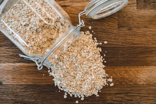 Free Close-up of rolled oats spilling from a jar on a wooden surface, showcasing healthy food. Stock Photo