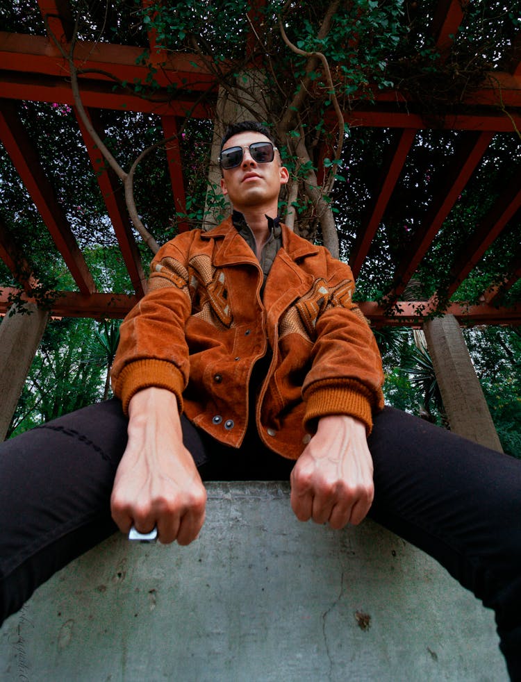 Man Sitting On Stone Posing In Garden