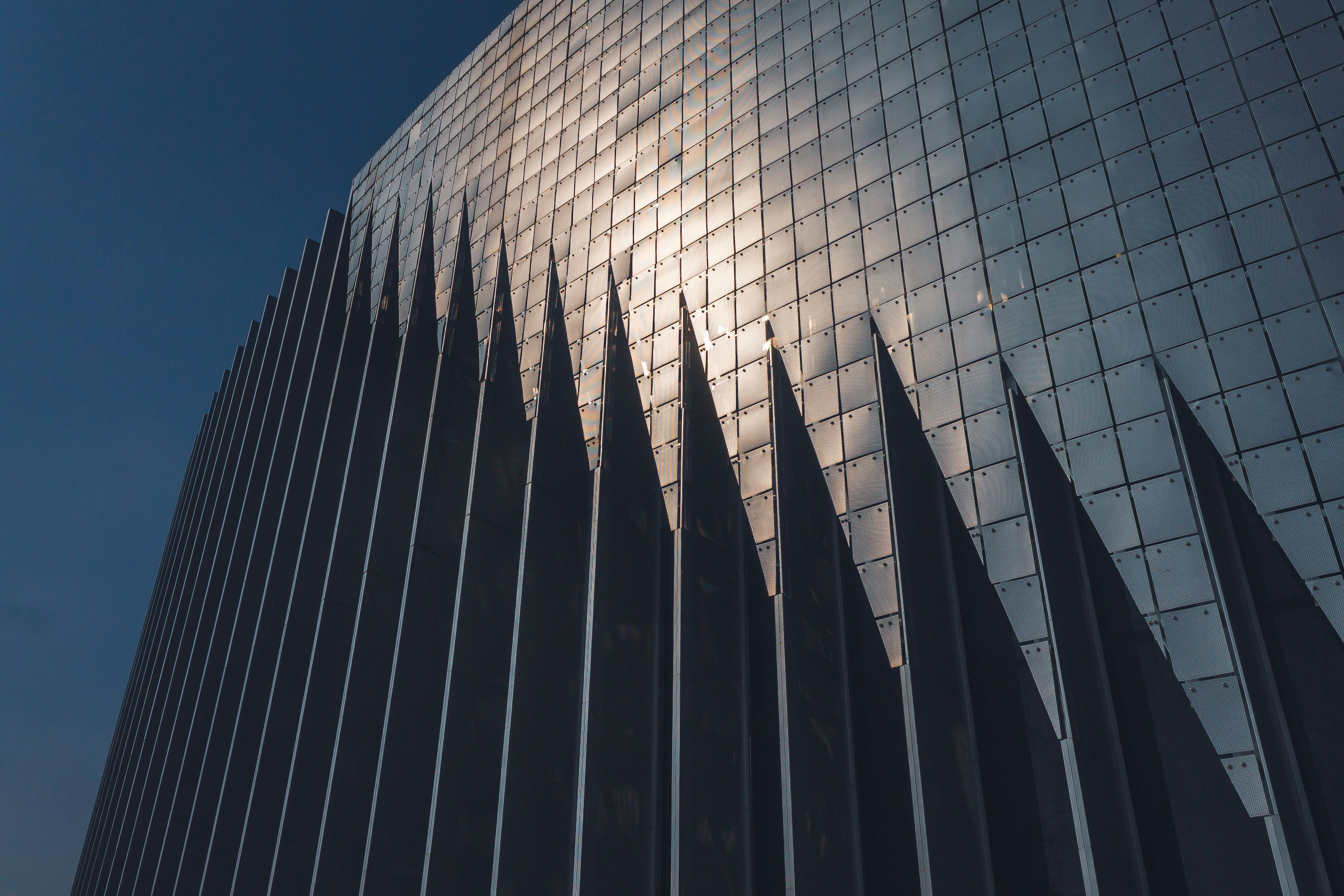 Striking modern building facade with sunlight reflecting off its angular design, creating a mesmerizing pattern.