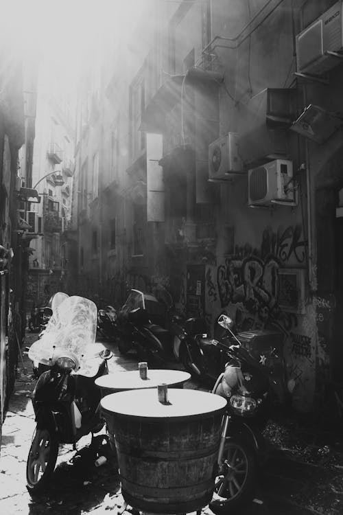 View of Motorcycles Standing in an Alley between Buildings with Graffiti 