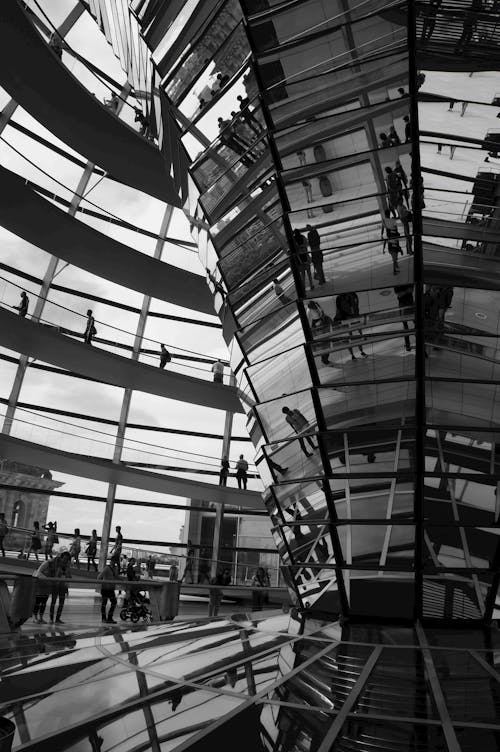 Grayscale Photo of People Inside a Glass Building