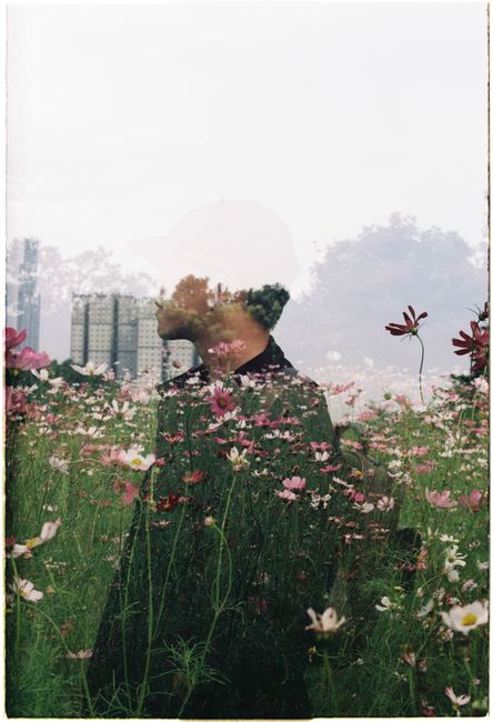 Double exposure of a man and a flower field against a cityscape backdrop.