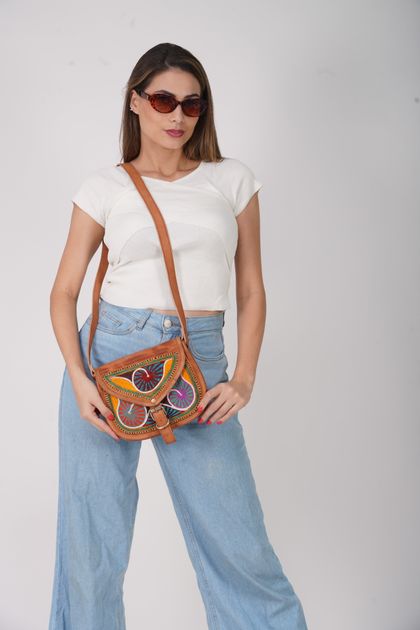 A model wearing a vibrant colorful handbag with tailored wide-leg jeans in a studio setting, demonstrating bold accessory styling