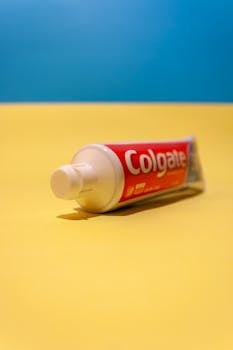 Close-up of Colgate toothpaste tube on vibrant yellow background, emphasizing oral hygiene.