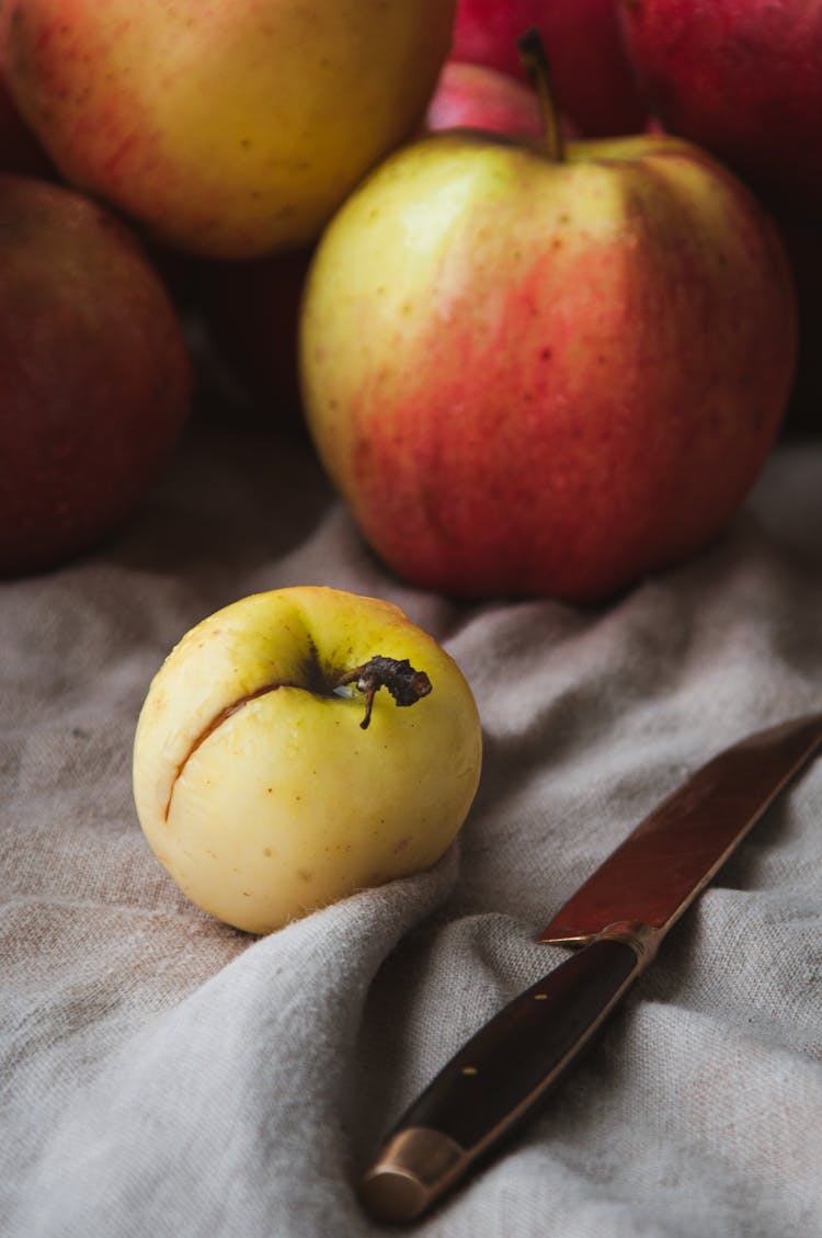 Red Apples And A Sharp Knife On Gray Fabric