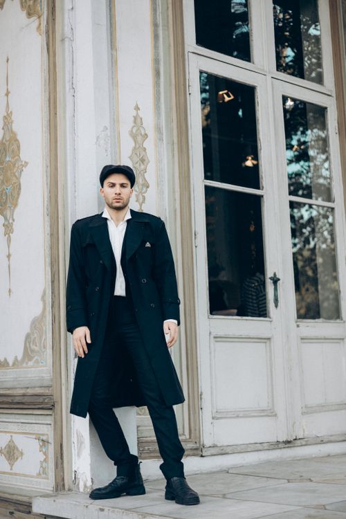 Free Stylish man in a trench coat standing by a grand entrance in Turkey, exuding elegance. Stock Photo