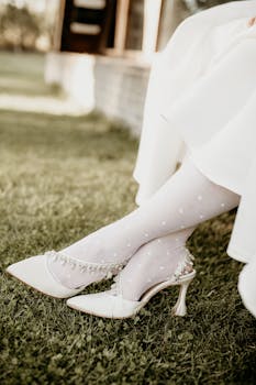 Close-up of bridal high heels and stockings on green grass, outdoors.