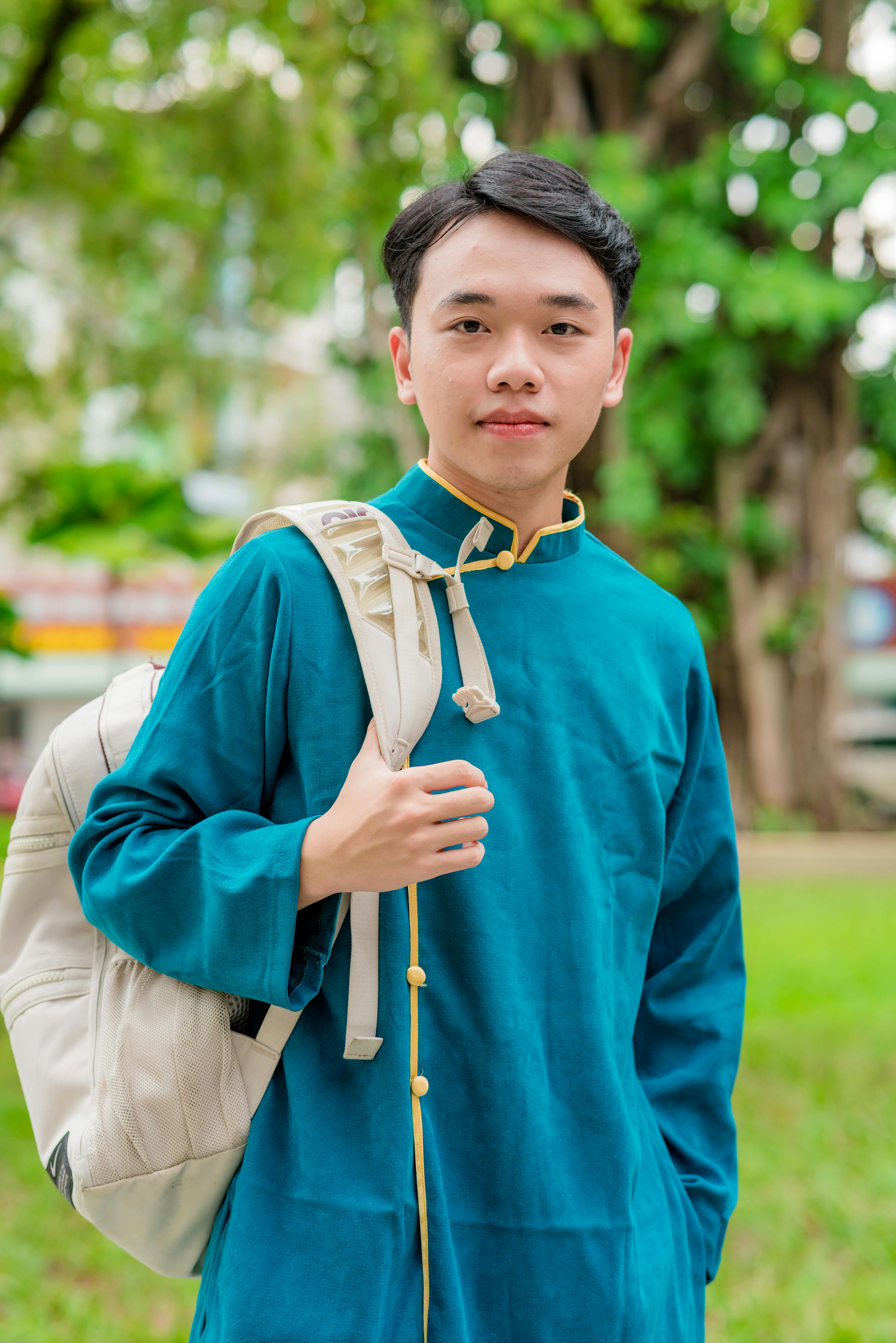 Portrait of a young boy in traditional attire carrying a backpack outdoors.