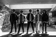 Black and white photo of a group of teenagers standing in an underground graffiti-covered tunnel.