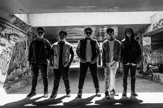 Black and white photo of a group of teenagers standing in an underground graffiti-covered tunnel.