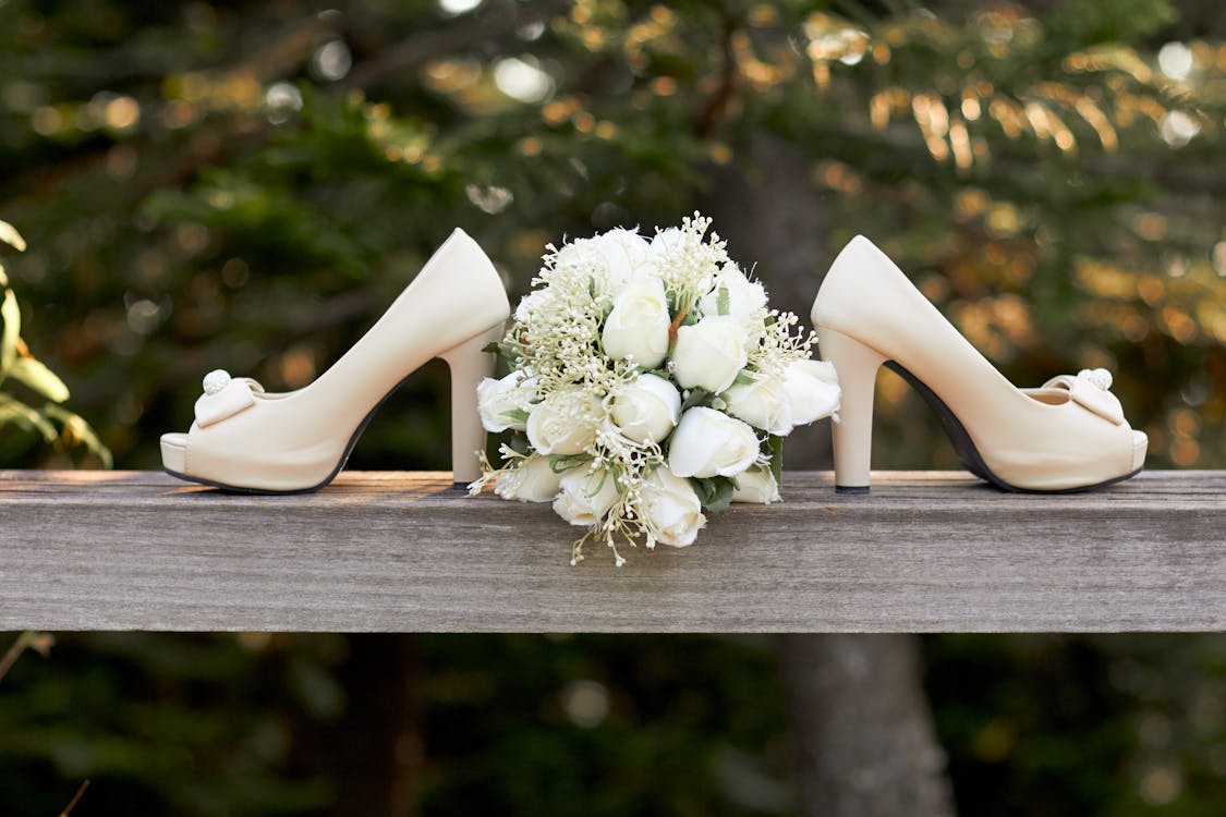 Free Selective Focus Photography of Pair of White Open-toe Chunky Heeled Shoes and Bouquet Flowers Stock Photo